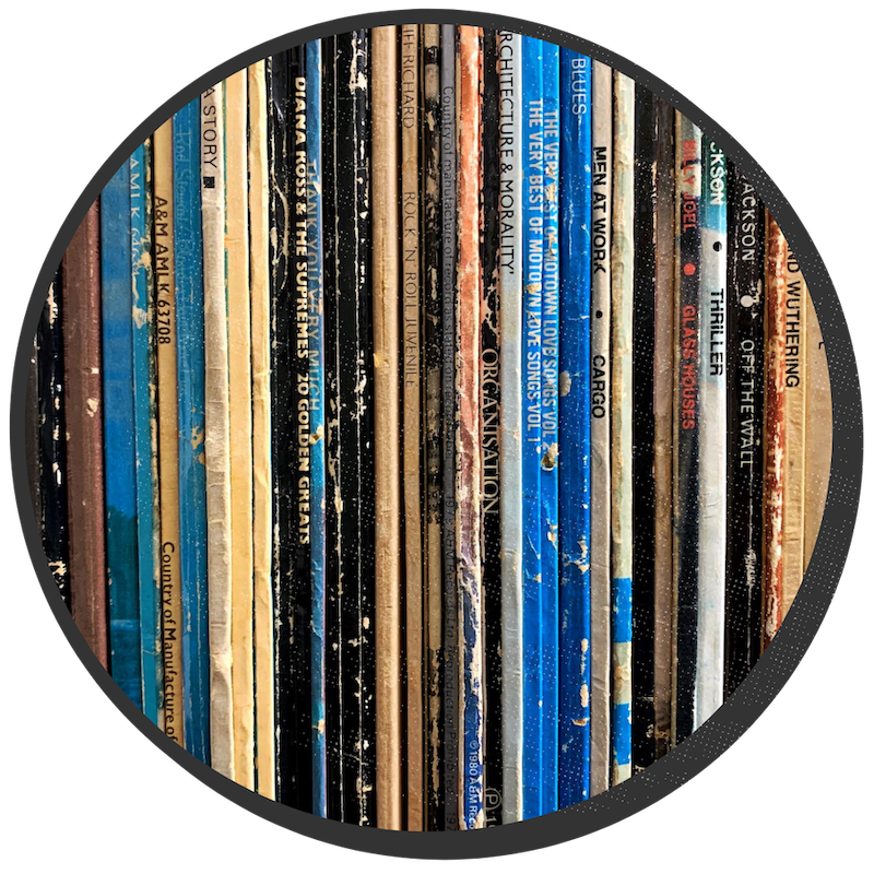 A close-up photo of tightly packed display of records lined up with their spines facing out. Some titles include Cargo by Men at Work, and Thriller by Michael Jackson.