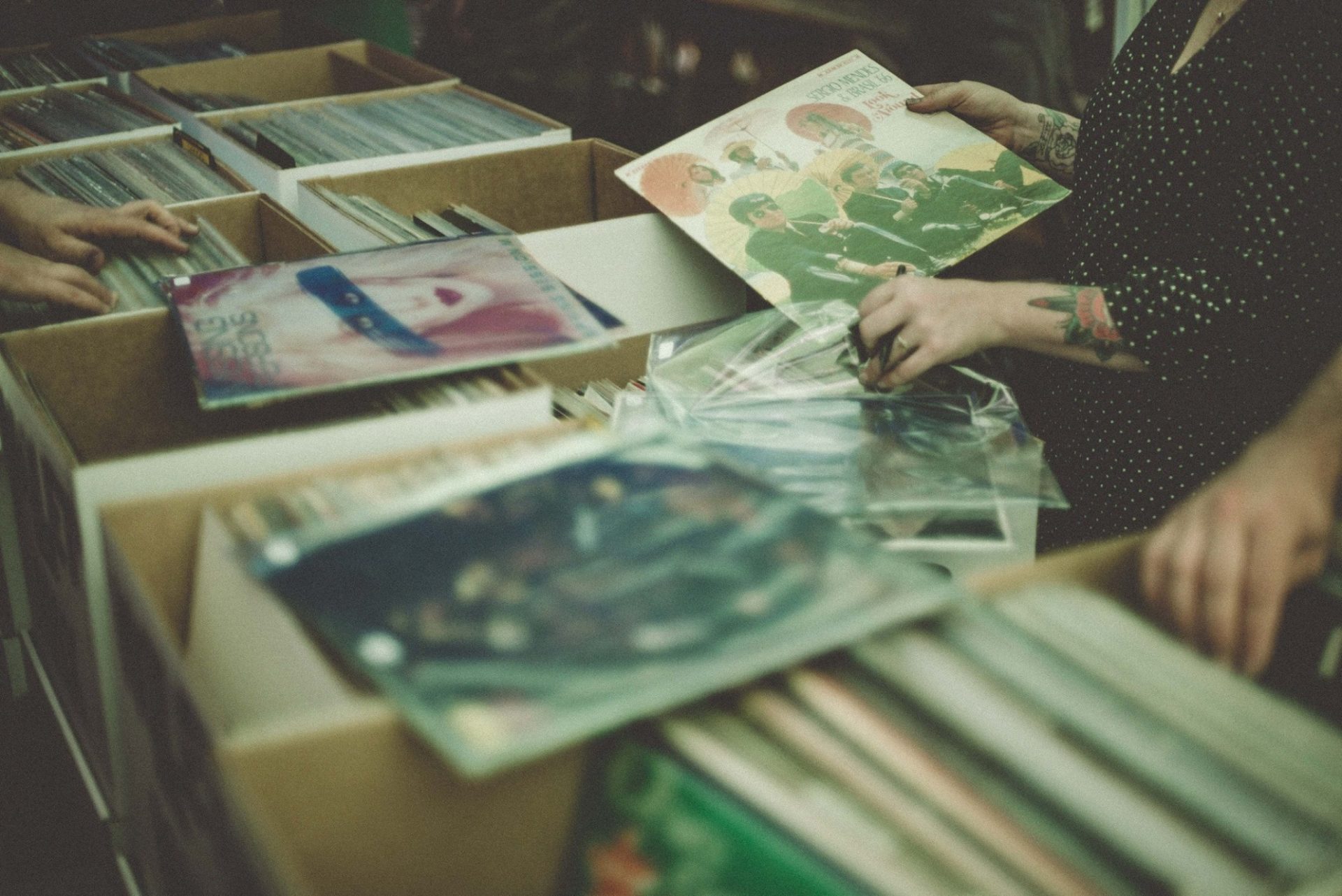 A photo of a person looking intently through records at a record store.