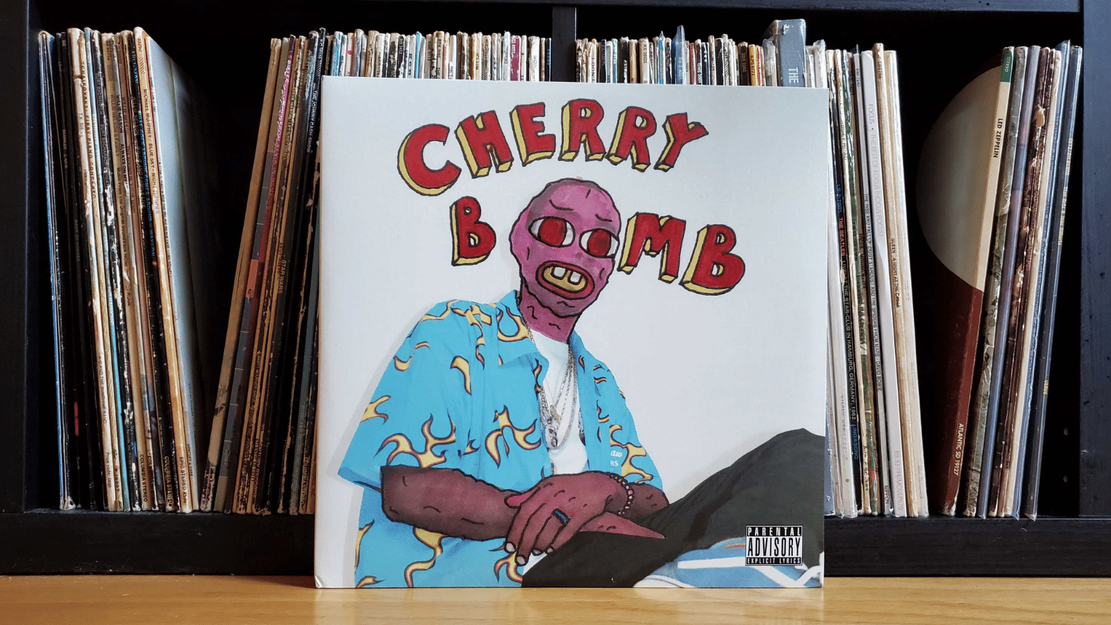 Tyler, the Creator vinyl cover leaning against a shelf filled with other vinyl records