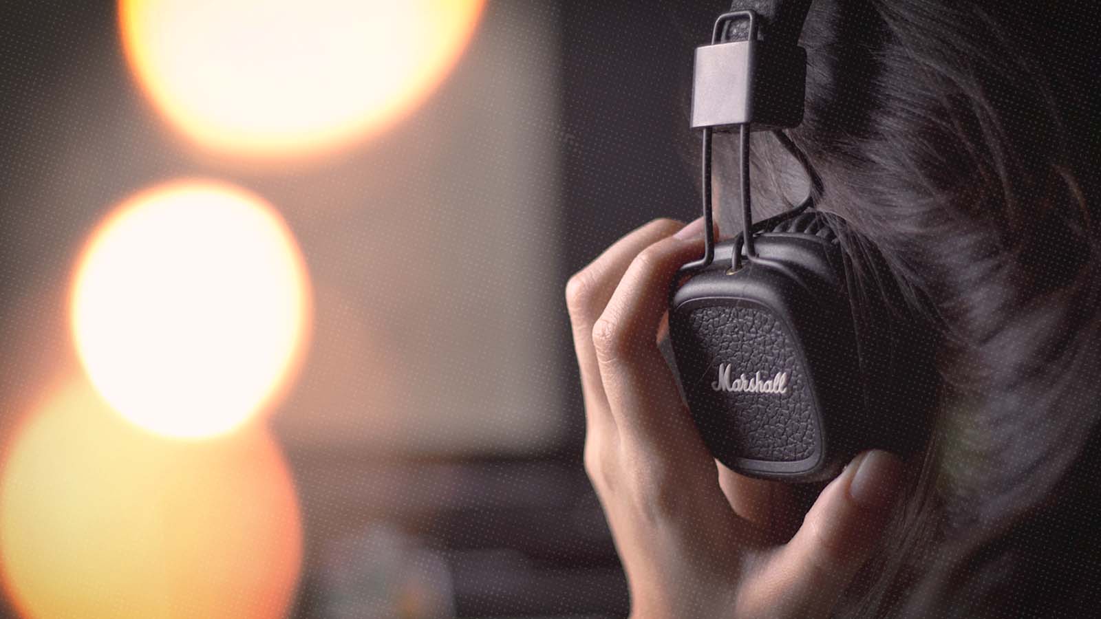 close up photo of a person wearing headphones with their hand on them