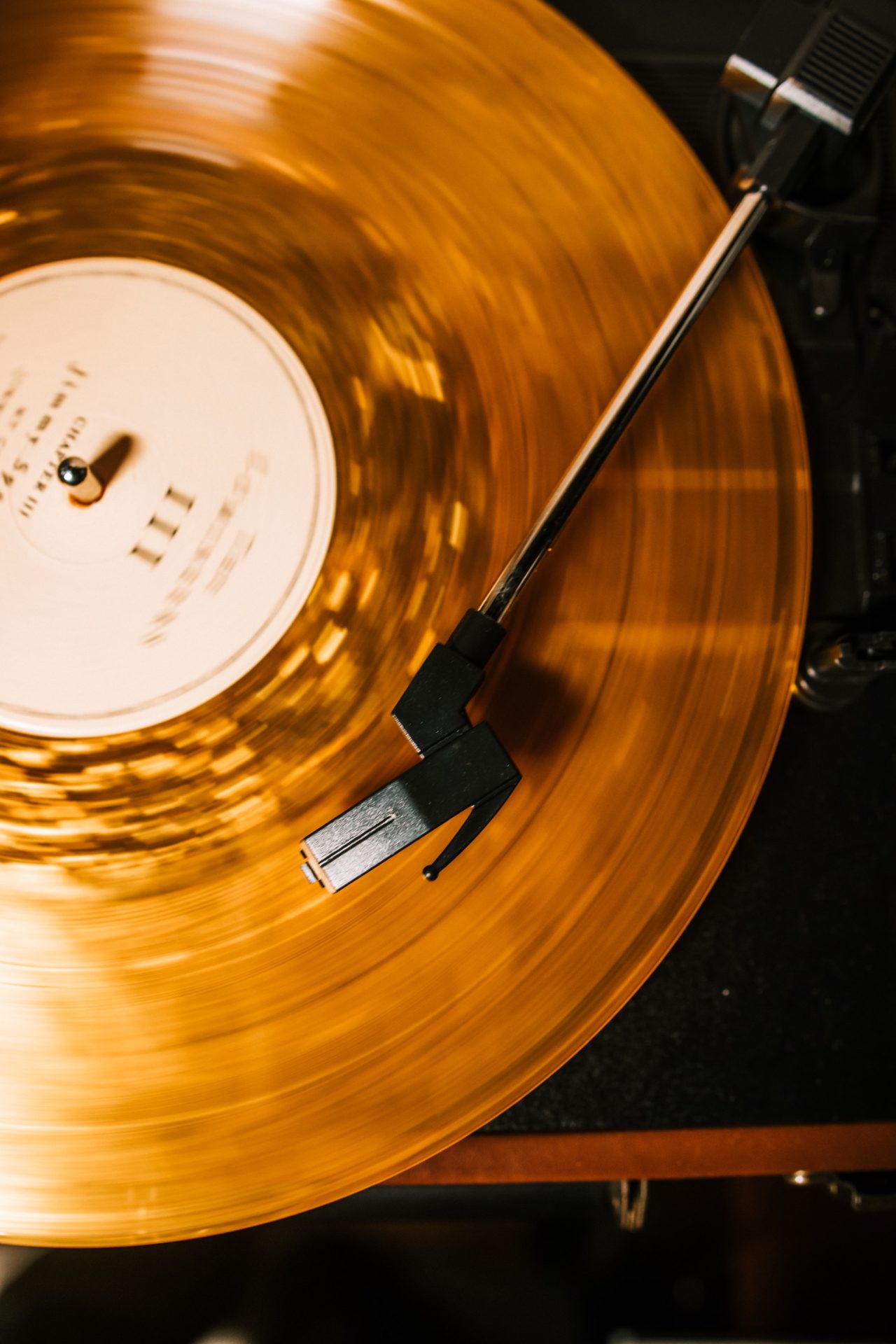 A picture of a yellow record spinning under a black stylus