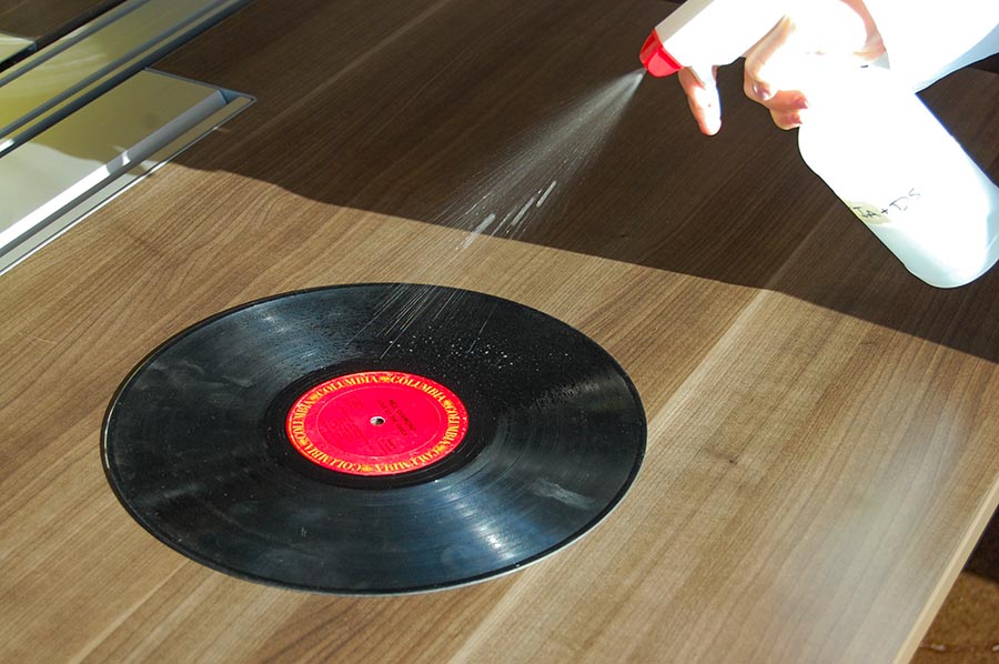 demonstrating the use of a spray bottle with vinyl record cleaner on to a black record