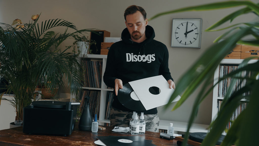 person demontrating how to properly handle vinyl records while putting them in a sleeve
