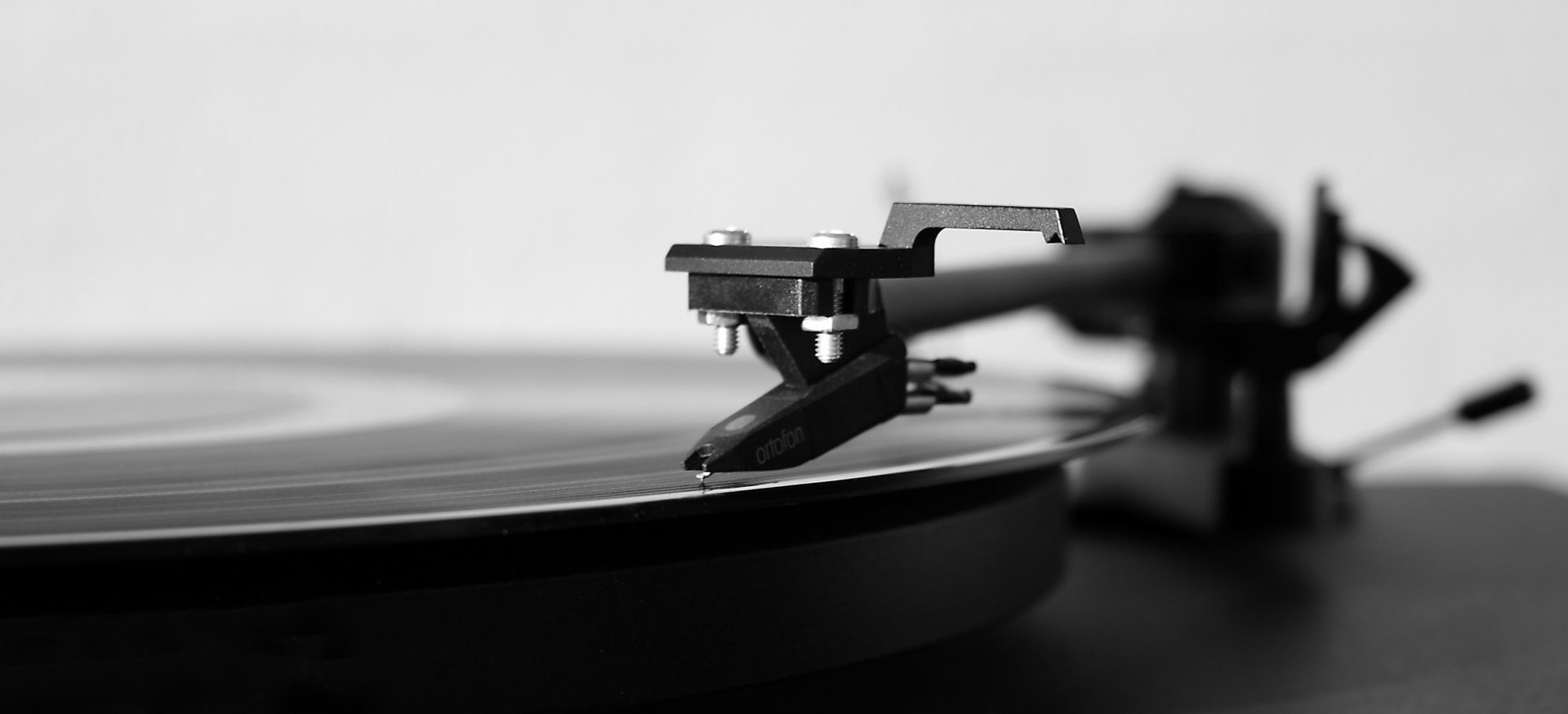 close up shot of a record player cartridge and stylus on a vinyl record