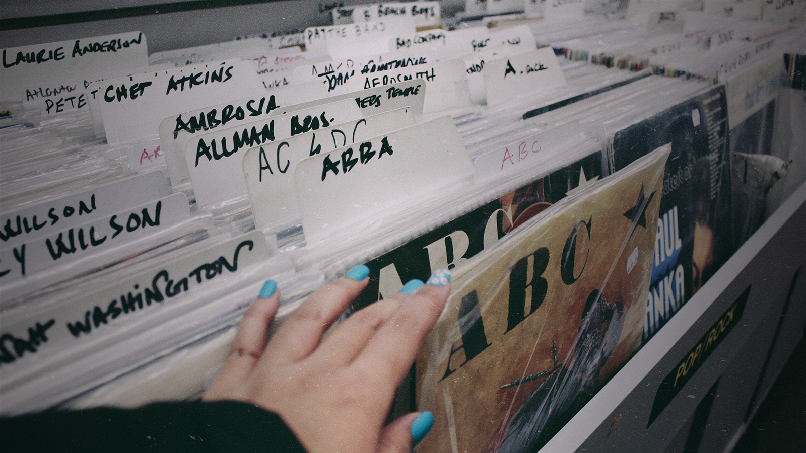 woman's hand reaching for vinyl in a record store